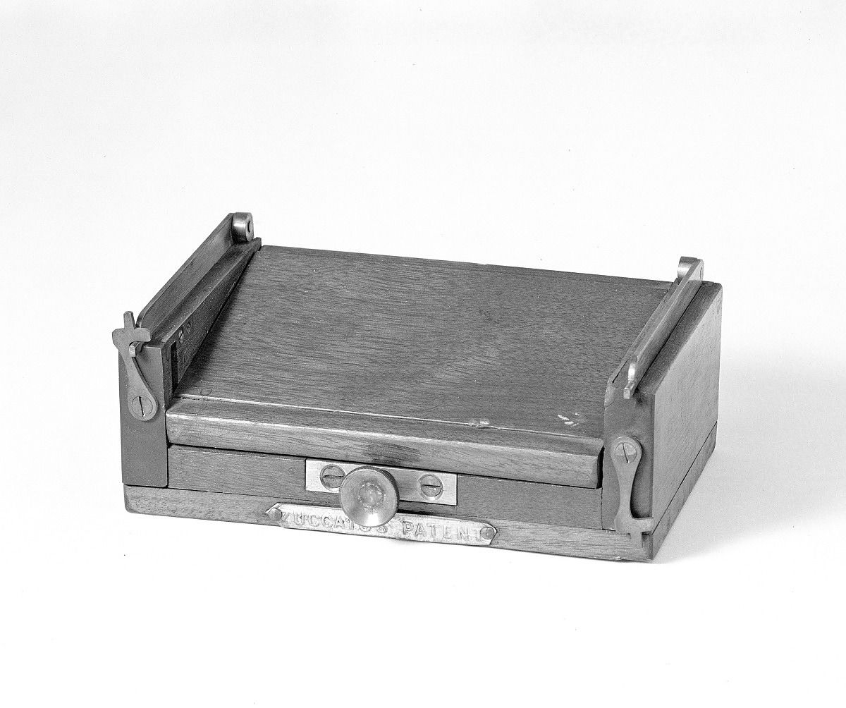 A wooden box with metal elements, like a lunchbox made of wood.