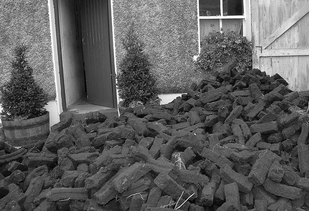 Sods of turf pile up against a cottage door. cc by Ballymore Bugle on Flickr.